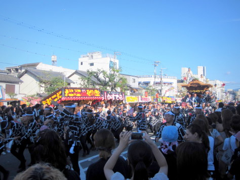 People pulling the danjiri while the man dances on top. I presume he is the most dispensable man in the town.